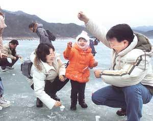 신재현씨(右)가 견지낚시로 빙어를 잡아올리자 딸 한별이와 부인 안경숙씨가 함박웃음을 지으며 즐거워하고 있다