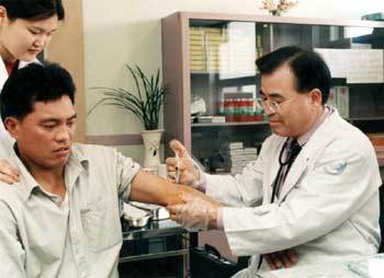 최윤근 교수(오른쪽)가 팔에 상처를 입은 필리핀 노동자를 치료하고 있다.