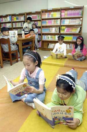 구남초등학교 학생들이 교내 도서실에서 학부모 자원봉사자의 도움을 받으며 책을 읽고 있다