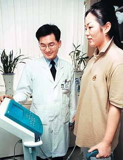 한 주부가 의사의 도움을 받으며 자신의 체지방율을 재고 있다.