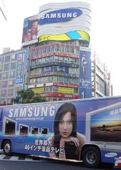 삼성 광고용 대형버스가 도쿄 시부야역앞의 삼성전자 초대형 옥외광고판 앞을 지나가고 있다.