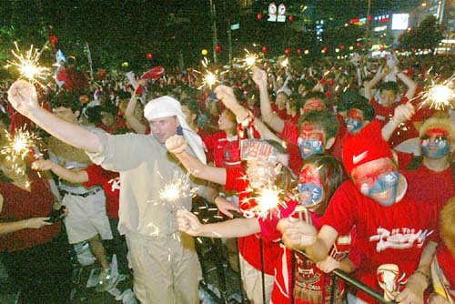 한국이 18일 8강행 티켓을 거머쥐자 서울 광화문 일대에 운집한 붉은 악마들이 일제히 불꽃놀이를 하며 환희에 넘치고 있다.