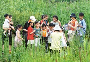 자연학습 교사로부터 물가에서 잡은 곤충들의 생김새에 대한 설명을 듣는 어린이들 [사진=변영욱기자]