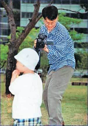 공원에 놀러 나온 한 아버지가 아들의 노는 모습을 디지털카메라에 담고 있다. LCD화면으로 찍히는 모습을 관찰해가며 촬영하고, 잘못 찍히면 쉽게 지울 수 있어 편리하다. /동아일보 자료사진