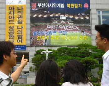 부산아시아경기대회 개막이 한 달 앞으로 다가온 가운데 부산시청에 걸린 북한선수단 환영 현수막을 시민들이 관심 있게 지켜보고 있다.