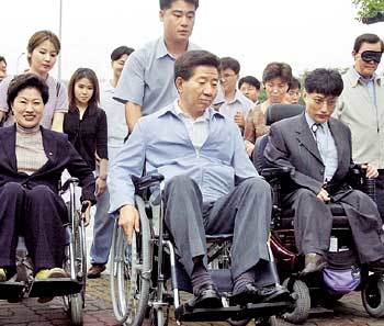 민주당 노무현 대통령후보가 1일 장애체험 행사에 참석해 장애인들과 함께 휠체어를 타고 있다. - 박경모기자