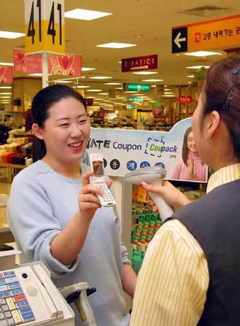 한 주부가 할인점에서 물건을 산 뒤 모바일 쿠폰을 점원에게 제시하고 있다. 쿠폰 대상 품목은 보통 5∼15% 할인된다. 사진제공 SK텔레콤