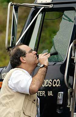 미국 버지니아주 경찰과 연방수사관들이 총에 맞아 옆 유리가 깨진 트럭을 살펴보고 있다. - 마나사스로이터연합