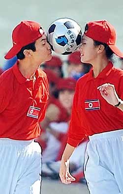 북한응원단의 노동당 창건 기념 체육대회에서 남녀 응원단원이 '통일 축구공'을 이마에 맞대고 달리기 놀이를 하고 있다. - 연합