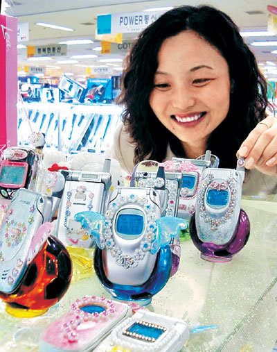 한 여성이 튜닝 전문숍에서 큐빅과 발광다이오드(LED)로 튜닝한 휴대전화를 살펴보고 있다. -사진제공 테크노마트