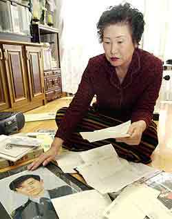 아들 박충훈씨가 한 장애인단체의 교사 학생들과 주고받은 편지를 보면서 아들의 사진을 어루만지고 있는 조공자씨. - 전영한기자