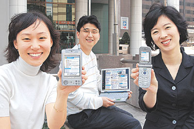 ‘네이트온(nateon.nate.com)’을 이용해 무선랜 기능의 노트북PC와 PDA 휴대전화로 채팅을 하던 직장인들이 각자 자신의 단말기를 들어 보이고 있다. 네이트온은 시범서비스 중이며 12월 중 정식 서비스할 예정이다.사진제공 SK커뮤니케이션즈