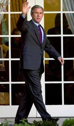 조지 W 부시 미국 대통령이 15일 미 해군 1호 헬리콥터에 탑승하기 위해 백악관 집무실을 나와 걸어가면서 기자들에게 손을 흔들고 있다. - 워싱턴AP연합