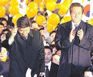 18일 밤 민주당 노무현 후보(왼쪽) 지지를 철회하기 직전 서울 명동에서 열린 노 후보와의 공동 거리 유세에 참석한 국민통합21 정몽준 대표가 박수를 치고 있지만 어두운 표정을 짓고 있다.연합