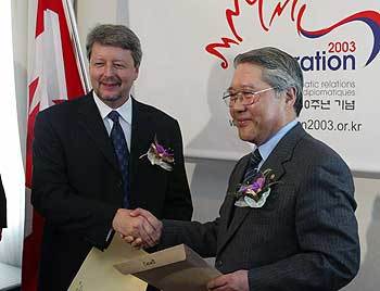 14일 주한 캐나다대사관저에서 열린 한국-캐나다 수교 40주년 기념식에서 최성홍 외교통상부장관(오른쪽)이 김대중대통령의 축하메시지를 드니 코모 주한 캐나다대사에게 전달하고 있다. -박윤석기자