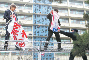 한총련 소속 대학생 2명이 26일 오전 서울 종로구 미국대사관 담 위에서 전쟁 중단 등을 요구하는 플래카드를 펼치려다 경찰의 제지를 받고 있다. -연합