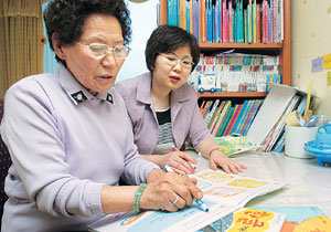 72세의 정옥심 할머니가 유아학습프로그램 교사인 이정환씨로부터 한글을 배우고 있다. 평생 써 본 일이 없다가 책을 읽기 위해 최근 마련한 안경을 쓰고 있다.용인=신석교 기자 tjrry@donga.com