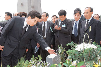 노무현 대통령이 18일 제23주년 5·18 기념식에 참석해 한 희생자의 묘비를 어루만지고 있다.-광주〓김경제기자 kjk5873@donga.com