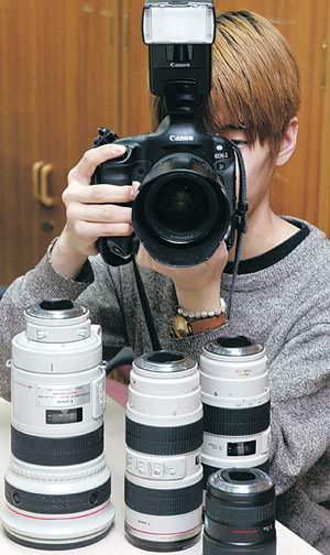 렌즈를 필요에 따라 바꿔 쓸 수 있는 디지털 SLR 카메라가 마니아들에게 인기를 끌고 있다. 한 사용자가 교환식 렌즈를 연결한 디지털 SLR 카메라를 조작하고 있다. 강병기기자 arche@donga.com