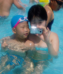 디지털카메라가 휴가철 필수 소품으로 떠오르고 있다. 14일 한 가족이 서울 시내 수영장에서 디지털카메라로 찍은 사진을 검색하고 있다. 이종승기자