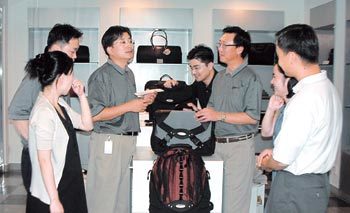 노트북컴퓨터용 가방 전문업체 TY월드의 김희범 회장(오른쪽에서 세번째)과 직원들이 자사 제품을 놓고 제품 개발에 대한 의견을 나누고 있다. 사진제공 TY월드