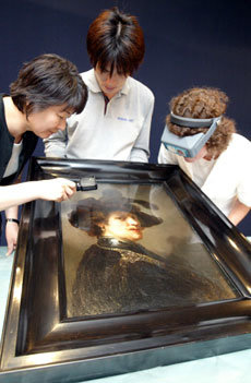 ‘깃 달린 모자를 쓴 남자’라는 작품을 두고 미술관 직원들이 손상여부를 살펴보고 있다. -박주일기자