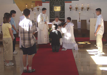 수도생활 체험학교 참가자 중 한 명이 입회식에서 무릎을 꿇은 채 신부에게 수도자의 생활을 충실히 따르겠다는 약속을 하고 있다. -왜관=서정보기자