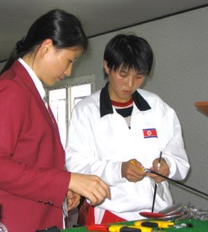 “칼 좀 고쳐주세요.” 대구하계유니버시아드에 출전한 북한의 한 여자 펜싱선수(오른쪽)가 21일 대구전시컨벤션센터에 있는 펜싱경기장 장비검사소에서 한국 관계자에게 칼을 보여주며 고장난 부분을 말해 주고 있다. 대구=연합