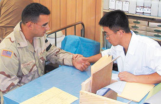 이라크에 파견된 국군 제마부대(의료부대)의 유일한 한방 의무병인 서영태 상병(오른쪽)이 한 미군병사를 진료하며 손목의 맥을 짚고 있다. -사진제공 국방부