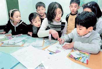 학습지를 선택할 때는 공부를 위한 것인지, 창의성을 계발하기 위한 것인지 목적을 분명히 한 뒤 자녀의 의견을 들어 함께 고르는 것이 좋다. 어린이들이 교사와 함께 학습지를 보며 공부하고 있다.