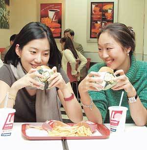 패스트푸드 업계에 건강식 바람이 불고 있다. 밀가루에 통호밀을 섞어 영양분을 강화한 호밀빵 햄버거를 여학생들이 맛보고 있다. 사진제공 롯데리아