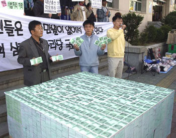 한국대학총학생회연합(한총련) 산하 부경총련 소속 대학생들이 30일 부산 남구 대연동 한나라당 김무성 의원 사무실 앞에서 가짜 1만원권 지폐로 100억원을 쌓아놓고 SK비자금 한나라당 유입에 대해 항의 시위를 벌였다. -부산=최재호기자