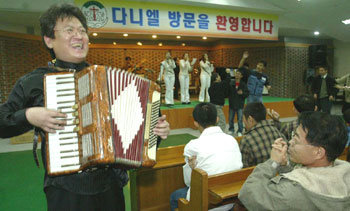 25일 서초구 내곡동 다니엘 복지원에서 200번째 장애인 복지원 방문공연을 하는 우광혁 교수와 음악봉사단체 ‘빛소리 친구들’. 100여명의 장애인들이 음악에 맞춰 춤을 추고 있다. -원대연기자