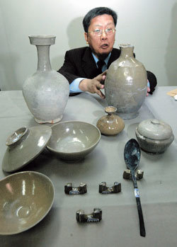 24일 오전 문화재연구소에서 열린 설명회에서 명지대 윤용이 교수가 이번 발굴에서 나온 편병(둥근 몸체에 한쪽만 편평한 자기)을 살피고 있다. 주둥이가 넓은 광구병(윤 교수 왼쪽), 숟가락 젓가락 받침대(앞쪽 가운데) 등 특이한 유물도 인양되었다. -김동주기자