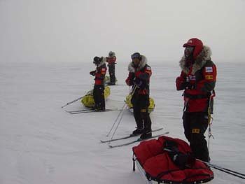 화이트 아웃 속에서의 휴식. 바람을 등지고 스키를 신은 채 서서 쉬고 있다.
