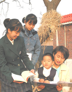 고정임씨가 아이들과 함께 집 뒤 살구나무에 걸터앉아 책을 읽고 있다.양주=김진경기자 kjk9@donga.com