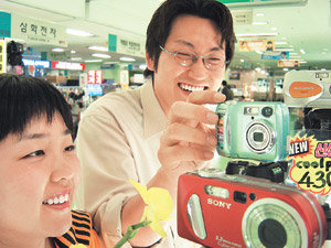 디지털카메라가 개인용 만능 정보기기로 떠오르고 있다. 사진 촬영은 물론 메모 입력, 영상 콘텐츠 제작 등까지 할 수 있어 쓰임새가 다양해지고 있다. 디지털카메라 매장을 찾은 고객들이 진열된 제품을 살펴보고 있다. 사진제공 테크노마트