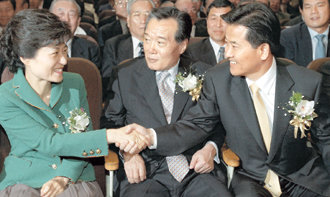 한나라당 박근혜 대표(왼쪽)와 열린우리당 정동영 의장(오른쪽)이 8일 서울 잠실 재향군인회관에서 악수하고 있다. 두 사람은 이날 민주당 최명헌 사무총장(가운데)과 함께 재향군인회 제50차 정기총회에 초청받아 각각 축사를 했다. 축사 도중 박 대표에게는 17차례나 박수가 쏟아졌다. 반면 노인 폄훼 발언 때문에 정 의장에게는 일부 회원들이 욕설을 퍼붓기도 했다.   -연합