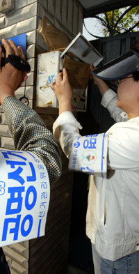 막판 선거전에 비방 흑색 유인물이 또다시 등장해 각 후보진영과 선거관리위원회를 긴장시키고 있다. 13일 서울 동대문구 선관위 관계자들이 용두1동 주택가에서 우편함 내 불법 유인물 투입 여부를 살펴보고 있다.   -서울=연합