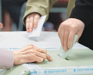 17대 총선에서 처음 도입된 1인2투표제에 따라 유권자들이 각각 후보와 정당을 찍은 투표용지를 두 개의 투표함에 한 장씩 나눠 넣고 있다. -강병기기자