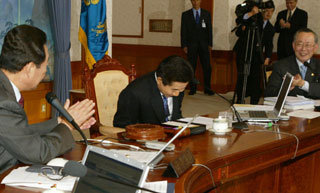 노무현 대통령(가운데)이 18일 오후 청와대에서 열린 국무회의에 앞서 고건 국무총리(왼쪽)를 비롯한 국무위원들이 대통령직 복귀를 축하하는 박수를 보내자 고개를 숙여 답례하고 있다.-박경모기자