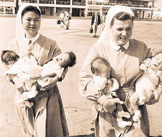 해외로 입양되기 위해 수녀들의 품에 안겨 비행기에 오르는 한국의 고아들. 1960년대에는 해외입양아들을 실어 나르기 위해 전세기가 뜰 정도였다.-동아일보 자료사진