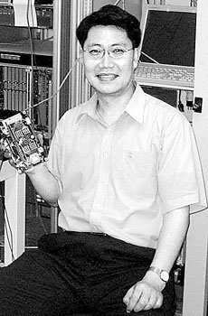 서울대 김수봉 교수가 중성미자 검출기의 전자신호를 처리하는 전자기판을 들고 있는 모습. 자체 개발한 이 전자기판은 300개로 이번 실험에 결정적인 역할을 했다. 배경의 장비들은 이들 전자기판을 테스트하는 데 쓰였다.