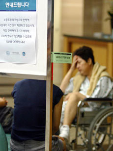 보건의료노조 파업 11일째인 20일 서울 종로구 연건동 서울대병원 로비에서 휠체어에 탄 한 환자가 지친 듯한 표정을 짓고 있다. 파업으로 수납대기 시간이 지연되고 있음을 사과하는 안내문이 붙어 있다.김미옥기자 salt@donga.com