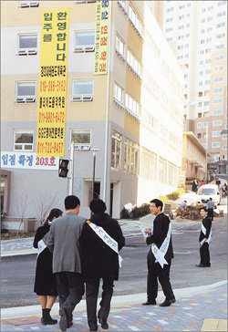 15일 경기 용인시 구성면 언남리 성원상떼빌 아파트단지 입구에서 어깨띠를 두른 국민은행과 제일은행 직원들이 주택담보대출을 받기 위해 상담에 나선 아파트 입주예정자를 잡기 위해 경쟁하고 있다. 용인=이철용기자