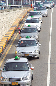 대전 택시사업조합 소속 택시운전사 1000여명이 19일 오후 대전 평송청소년수련원에서 ‘신행정수도 사수 결의대회’를 가진 뒤 택시를 몰고 주변을 돌며 경적시위를 벌이고 있다. 이들은 “행정수도를 원안대로 충청권으로 이전하라”고 촉구했다. 대전=연합