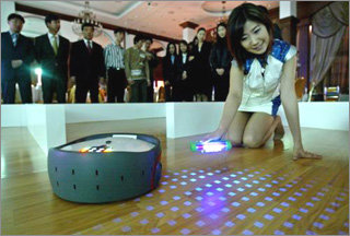 10일 서울 강남구 아미가호텔에서 공개된 위치 인식 청소로봇. 걸레질을 하는 로봇으로 바닥재에 인쇄된 투명 바코드를 읽어 위치를 인식한다. 사진을 찍기 위해 적외선을 쬐어 바닥에 있는 바코드가 드러나게 했다. 권주훈 기자