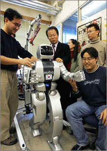 두 발로 자연스럽게 걷는 로봇 ‘휴보’를 개발한 오준호 교수(로봇 뒤)와 관련 연구원들.-사진 제공 한국과학기술원