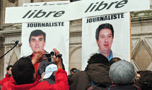 프랑스의 르 피가로 소속 말브뤼노 기자(오른쪽)와 RFI 라디오의 셰노 기자의 생환 기념 포스터 앞에서 환호하는 파리 시민들. 동아일보 자료 사진
