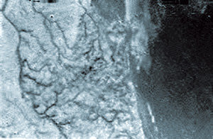 유럽우주국(ESA)이 15일 공개한 타이탄 표면의 사진. 호이겐스가 고도 16.2km 지점에서 촬영한 이 사진에는 액체가 흐른 듯한 협곡들이 검은 지역으로 이어지는 형태가 뚜렷하다. 흰 지역과 검은 지역의 경계는 마치 해안선처럼 보인다. AP 연합